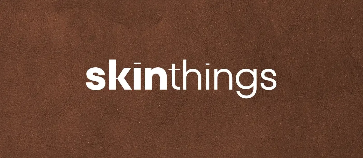 Lowercase skinthings wordmark in white on textured chocolate brown