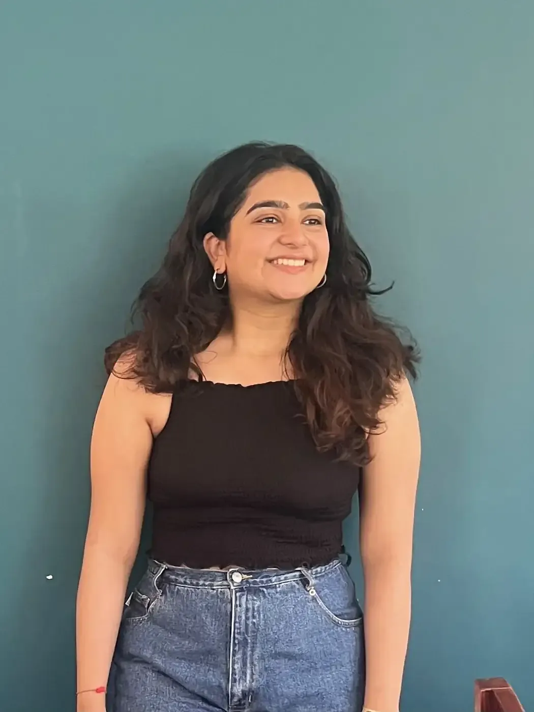 Karishma Gandhi, founder of Creative Chokri, smiling against a teal wall